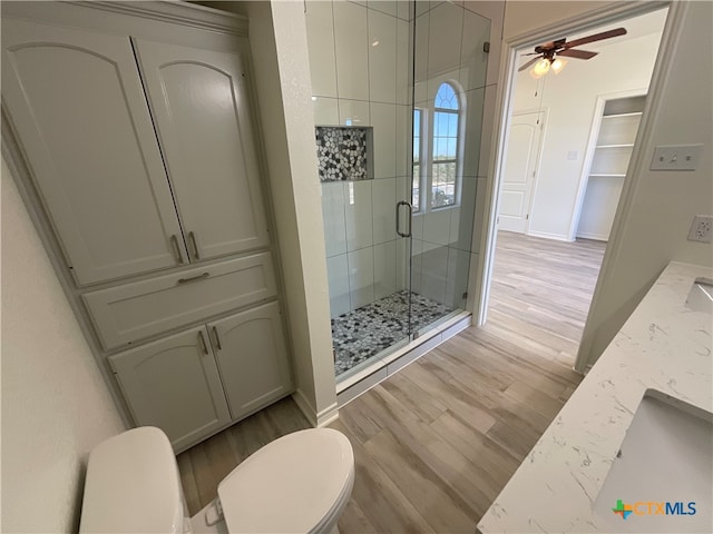 bathroom with walk in shower, ceiling fan, hardwood / wood-style floors, vanity, and toilet