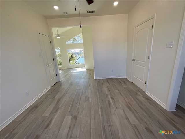 unfurnished dining area featuring light wood-type flooring, ceiling fan, and vaulted ceiling