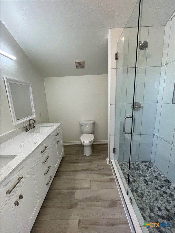 bathroom with toilet, vanity, hardwood / wood-style flooring, and a shower with door