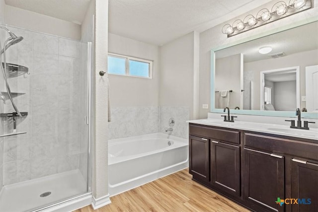 bathroom with vanity, a textured ceiling, wood-type flooring, and separate shower and tub