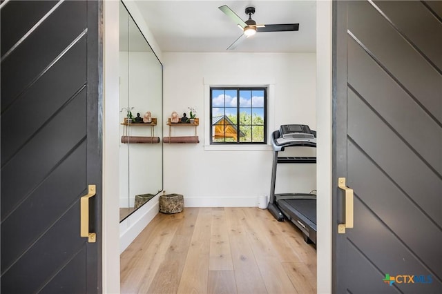 exercise room with baseboards, light wood-style floors, and a ceiling fan