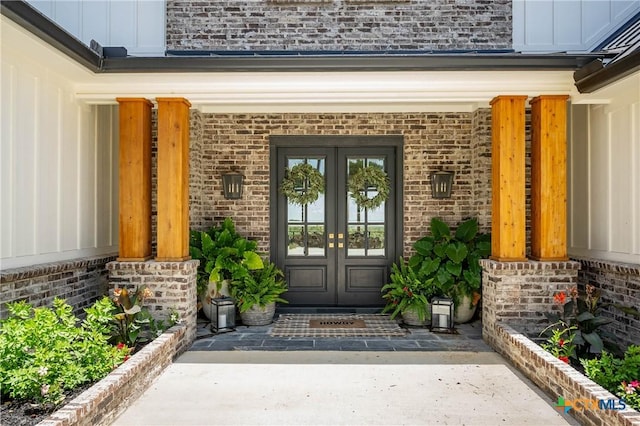 view of exterior entry featuring brick siding, french doors, and board and batten siding