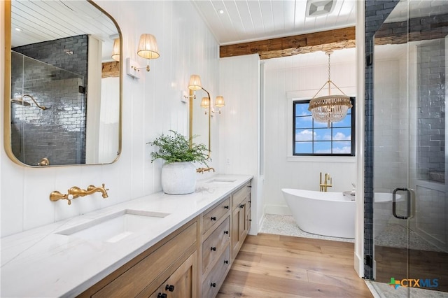 bathroom with double vanity, a shower stall, wood finished floors, and a sink