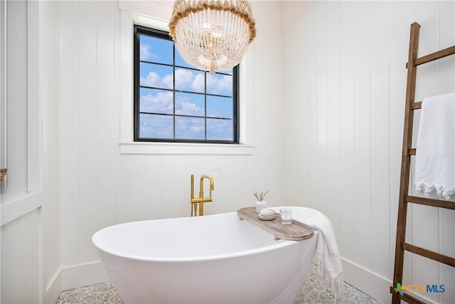 full bath featuring a soaking tub and a notable chandelier