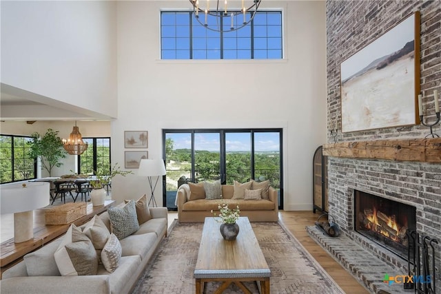 living room with wood finished floors, a fireplace, baseboards, and a chandelier