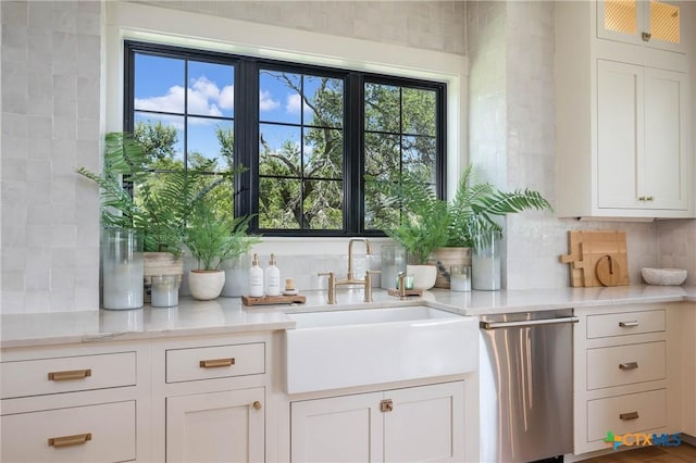 bar with decorative backsplash, dishwasher, and a sink