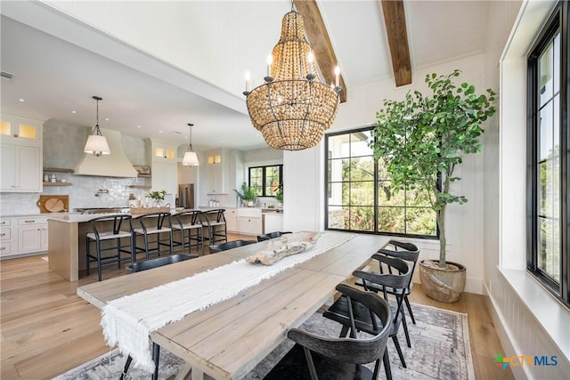 dining area with an inviting chandelier, beamed ceiling, light wood-style flooring, and visible vents