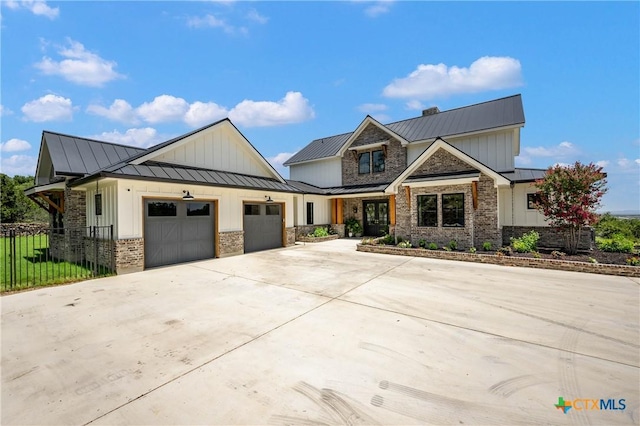 view of front of property featuring driveway, a standing seam roof, an attached garage, brick siding, and metal roof