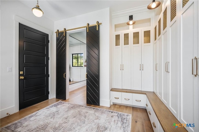 mudroom with a barn door, baseboards, and light wood-style flooring