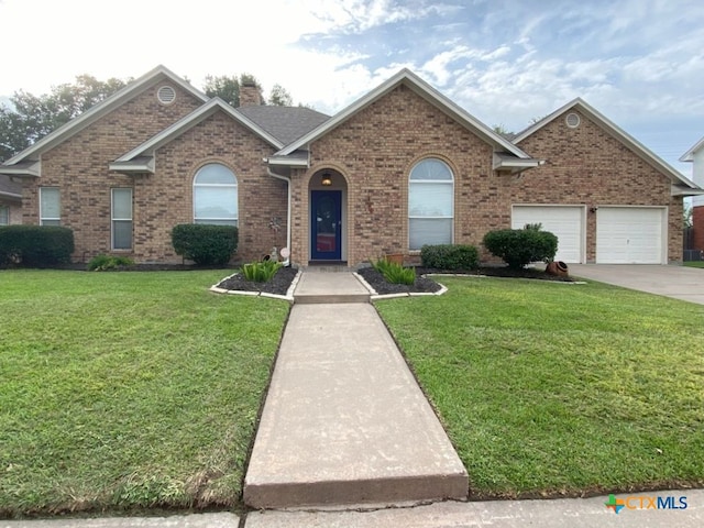406 Windy Way Dr, Victoria, TX 77904 - view of front facade featuring a front lawn, brick siding, a chimney, and concrete driveway