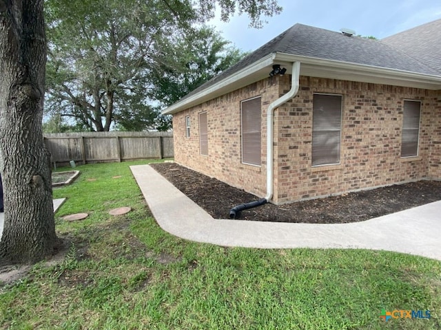 406 Windy Way Dr, Victoria, TX 77904 - view of home's exterior with a fenced backyard, roof with shingles, and brick siding