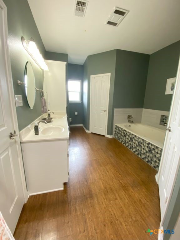 406 Windy Way Dr, Victoria, TX 77904 - bathroom featuring wood finished floors, double vanity, and a bath