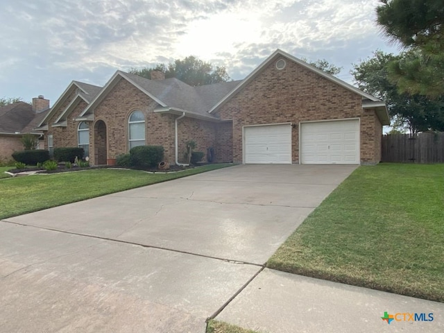 406 Windy Way Dr, Victoria, TX 77904 - view of front of house with brick siding, a chimney, concrete driveway, and a garage