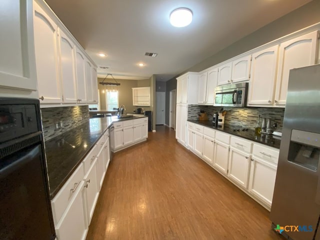 406 Windy Way Dr, Victoria, TX 77904 - kitchen with appliances with stainless steel finishes, a peninsula, white cabinets, dark wood finished floors, and backsplash