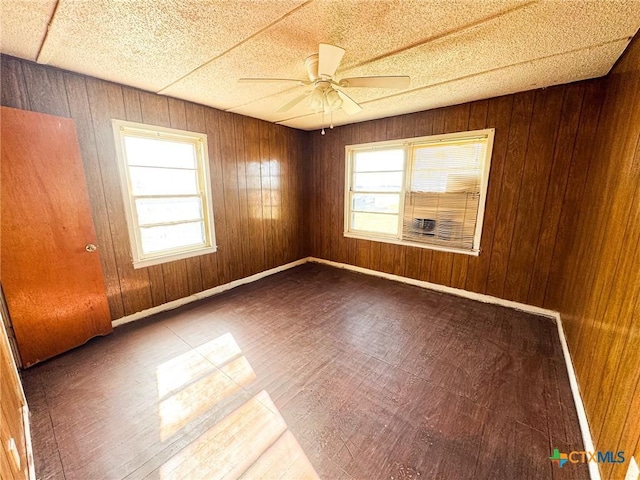 unfurnished room with hardwood / wood-style flooring, ceiling fan, and wood walls