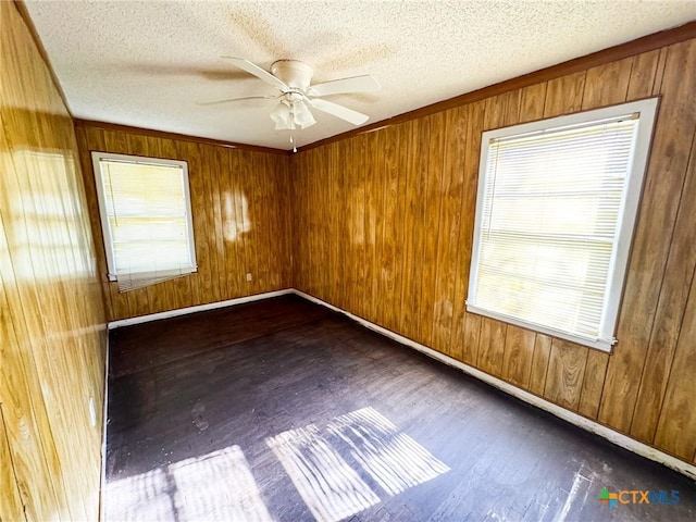 spare room with ceiling fan, dark wood-type flooring, and wooden walls