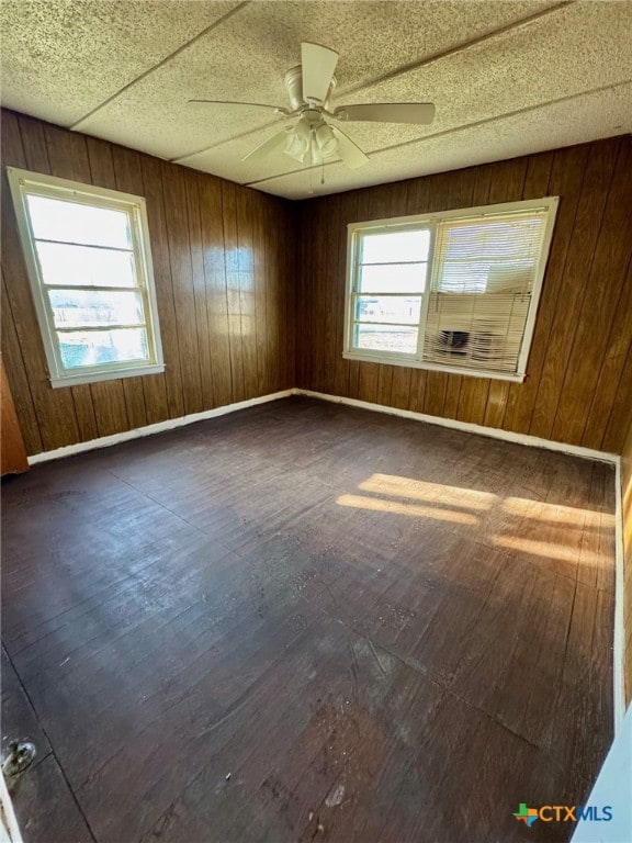 spare room with dark hardwood / wood-style floors, ceiling fan, and wood walls