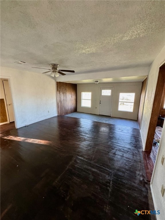 unfurnished living room with a wealth of natural light, ceiling fan, and a textured ceiling