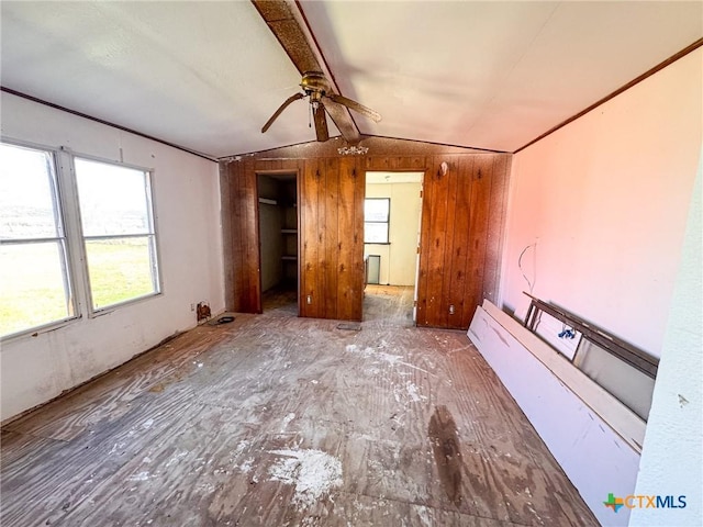 interior space featuring lofted ceiling with beams, ceiling fan, and wood walls