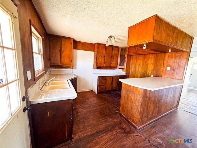 kitchen featuring kitchen peninsula, a textured ceiling, a wealth of natural light, and sink