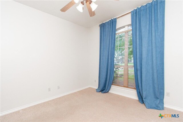 spare room featuring baseboards, light carpet, and a ceiling fan