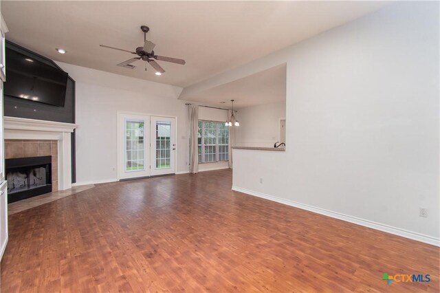 unfurnished living room with baseboards, wood finished floors, and ceiling fan with notable chandelier
