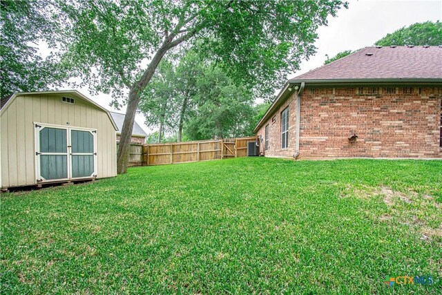 view of yard featuring a fenced backyard, a storage unit, and an outbuilding