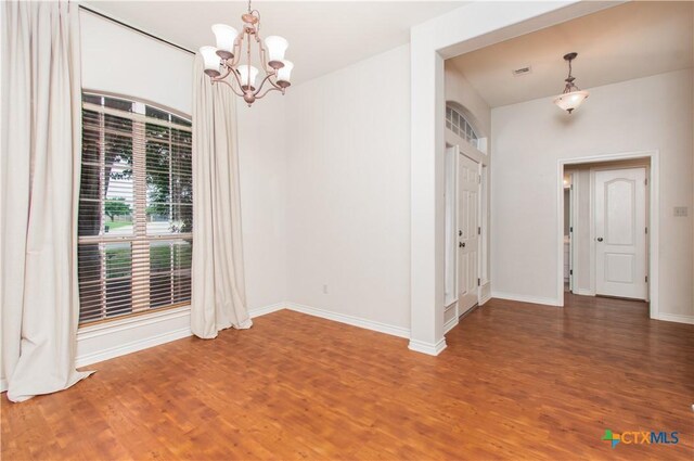 unfurnished dining area with baseboards, wood finished floors, and a chandelier