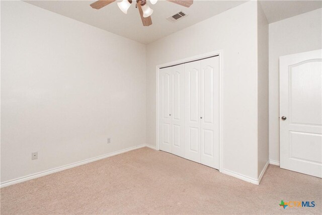unfurnished bedroom with baseboards, visible vents, a closet, and light colored carpet