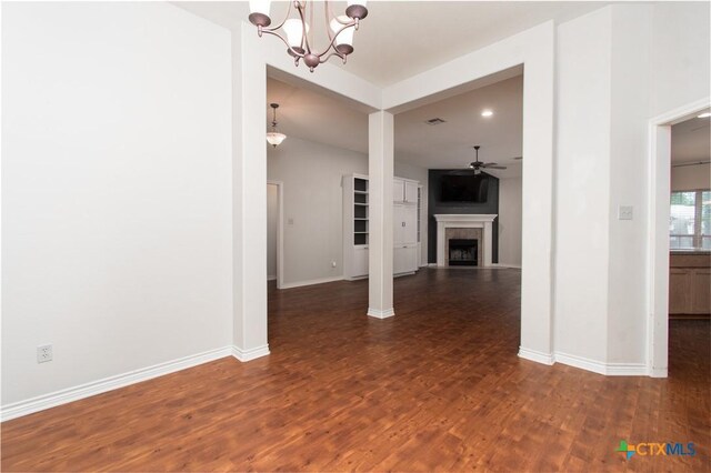 unfurnished living room with baseboards, a fireplace, ceiling fan with notable chandelier, and dark wood-type flooring