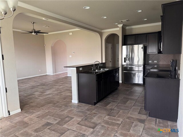 kitchen with dark countertops, backsplash, crown molding, appliances with stainless steel finishes, and a sink