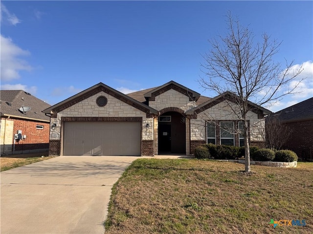 french provincial home with brick siding, driveway, an attached garage, and a front lawn