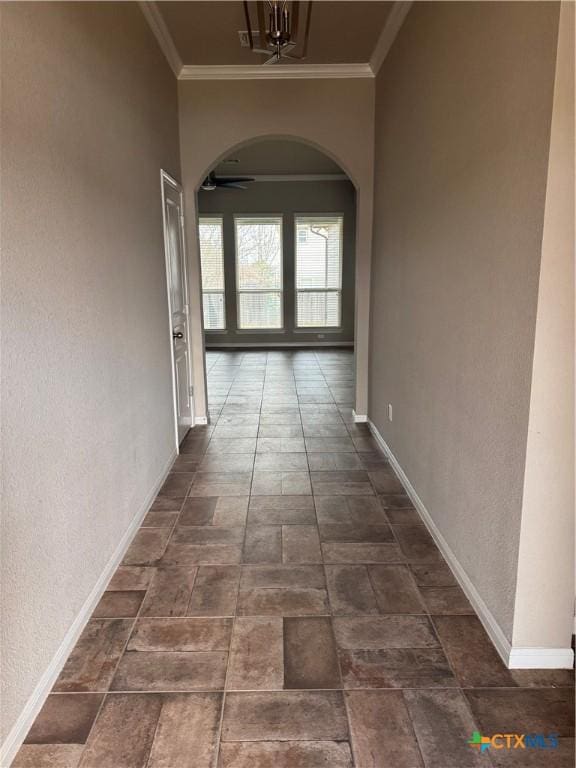 hallway with arched walkways, baseboards, and ornamental molding