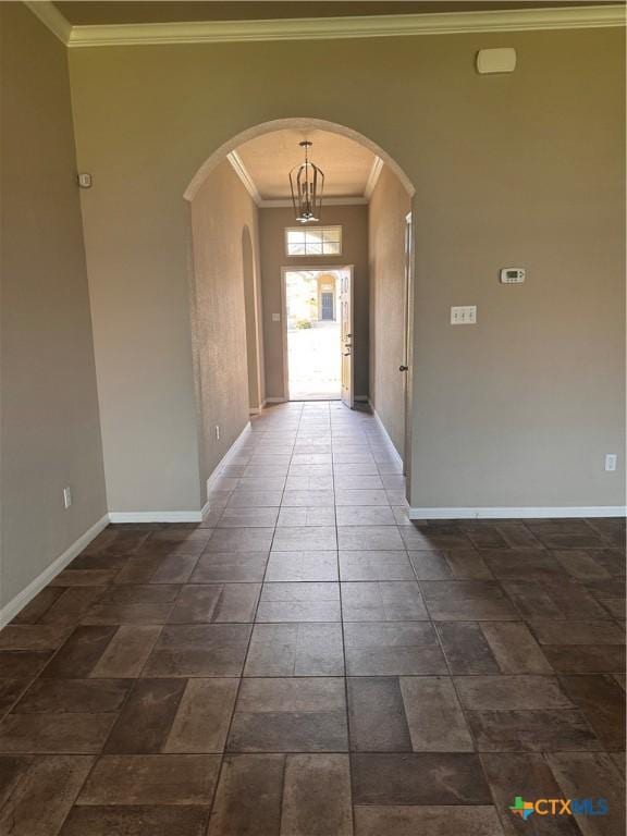 interior space featuring arched walkways, crown molding, and baseboards