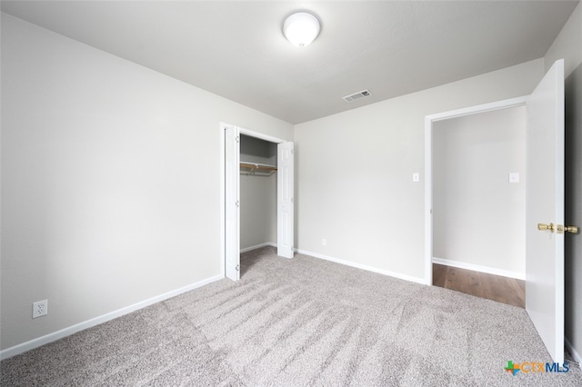 unfurnished bedroom featuring light carpet and a closet