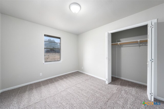 unfurnished bedroom featuring carpet flooring and a closet