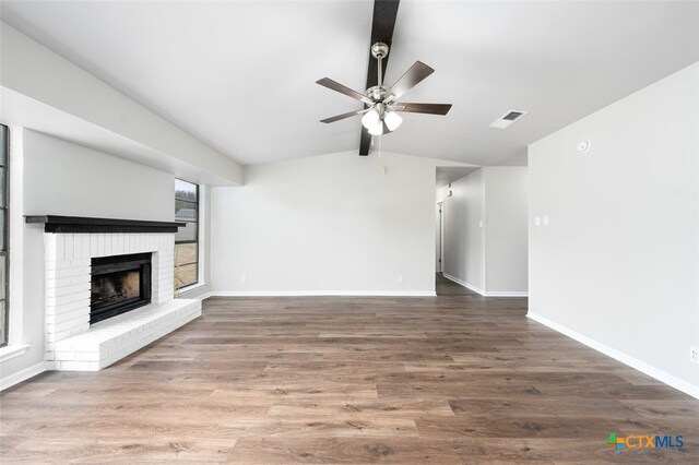 unfurnished living room featuring ceiling fan, hardwood / wood-style floors, vaulted ceiling with beams, and a brick fireplace