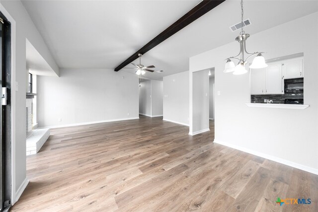 unfurnished living room featuring ceiling fan with notable chandelier, light hardwood / wood-style flooring, and lofted ceiling with beams