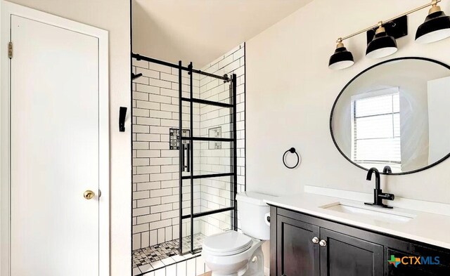 bathroom featuring vanity, toilet, and tiled shower