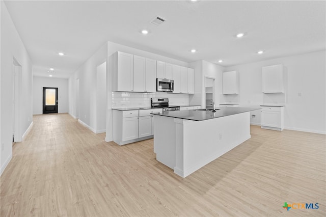 kitchen with a center island with sink, appliances with stainless steel finishes, light hardwood / wood-style flooring, sink, and white cabinets