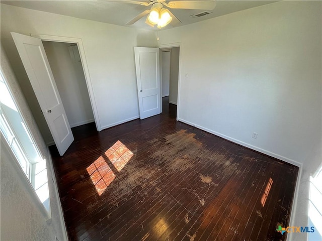 unfurnished bedroom with ceiling fan, visible vents, baseboards, a closet, and hardwood / wood-style floors