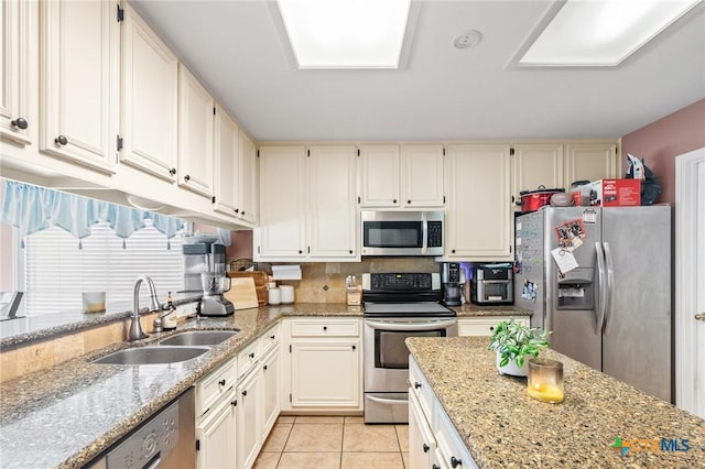 kitchen featuring a sink, light stone countertops, appliances with stainless steel finishes, and light tile patterned floors