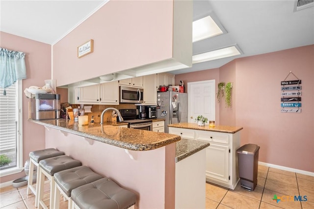 kitchen with stone countertops, a peninsula, visible vents, and stainless steel appliances