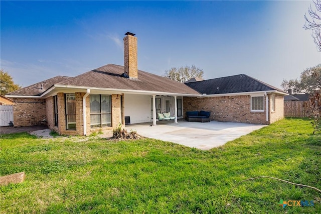 back of property with brick siding, a lawn, a patio, and fence