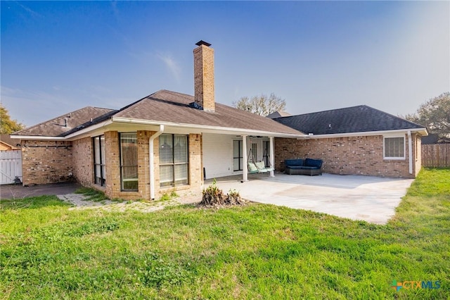 back of house with a patio, fence, a yard, a chimney, and brick siding