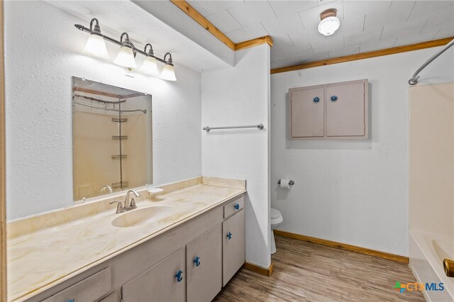 bathroom featuring ornamental molding, wood-type flooring, toilet, and vanity