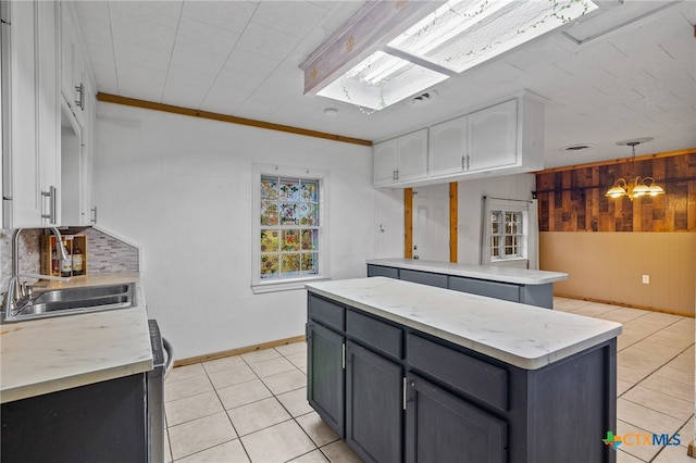 kitchen featuring sink, light tile patterned floors, a kitchen island, white cabinets, and decorative backsplash