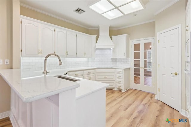 104 Twelve Oaks Dr, Temple, TX 76504 - kitchen featuring custom range hood, a peninsula, french doors, visible vents, and a sink