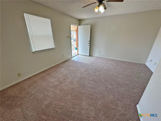 empty room with light carpet, ceiling fan, a textured ceiling, and baseboards