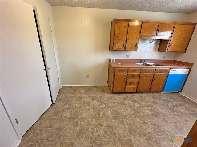 kitchen with dishwasher, brown cabinetry, a sink, and baseboards